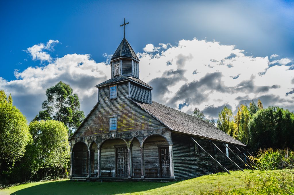 Iglesias patrimoniales de madera en Chiloé bajo un cielo nublado, sede del Seminario Internacional SICPAM.