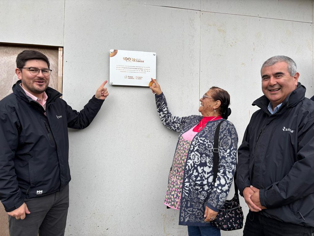 Vecinos y dirigentes participan en la inauguración de la nueva iluminación LED en la sede comunitaria de Bahía Mansa junto a ejecutivos de Saesa.